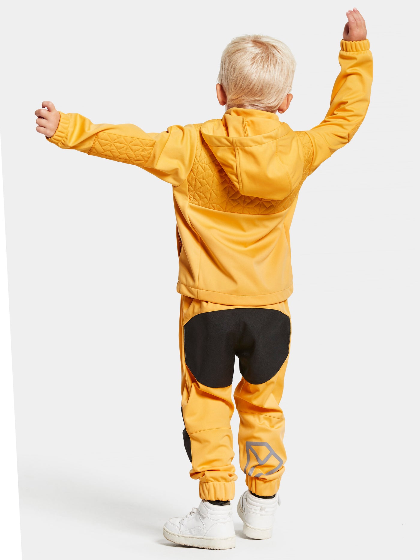 Didriksonsin lasten Briska hybriditakki keltaisessa sävyssä lapsen päällä takaa kuvattuna.