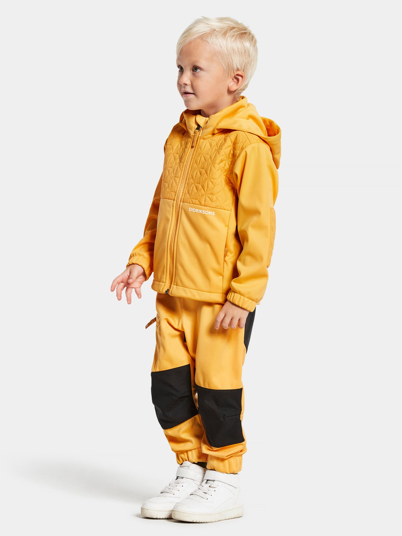 Didriksonsin lasten Briska hybriditakki keltaisessa sävyssä lapsen päällä hieman sivuttain kuvattuna. 