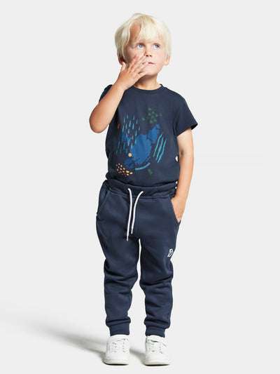 Didriksonsin Corin lasten housut tummansinisessä sävyssä lapsen päällä kauempaa edestä kuvattuna