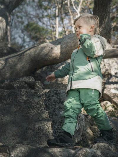 Poika seikkailee luonnossa Didriksonsin lasten Ash-takki päällä sävyssä Green Mist