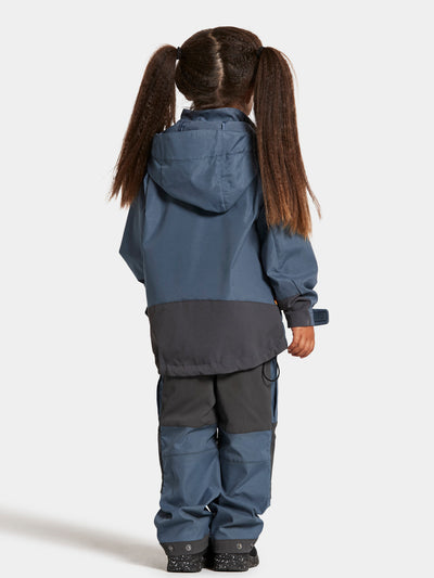 Tytön päällä Didriksonsin Stigen lasten sininen takki takaa kuvattuna