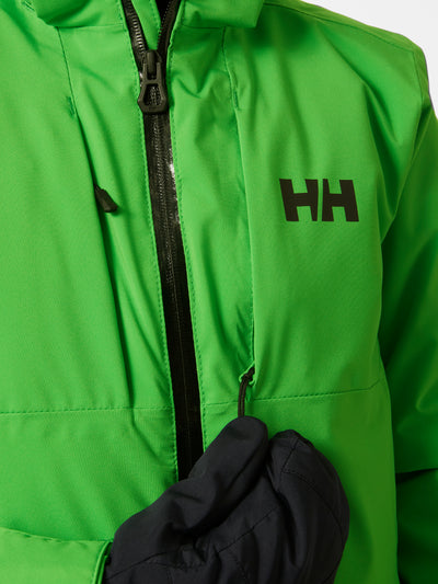 Helly Hansenin lasten ja nuorten Alpha-laskettelutakki kirkkaan vihreässä sävyssä lapsen päällä Helly Hansenin logo kuvattuna