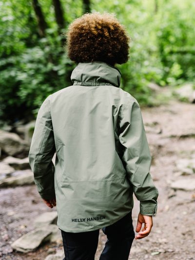 Helly Hansen Junior Loen takki värissä Forest Night pojan päällä takaa kuvattuna metsämaisema