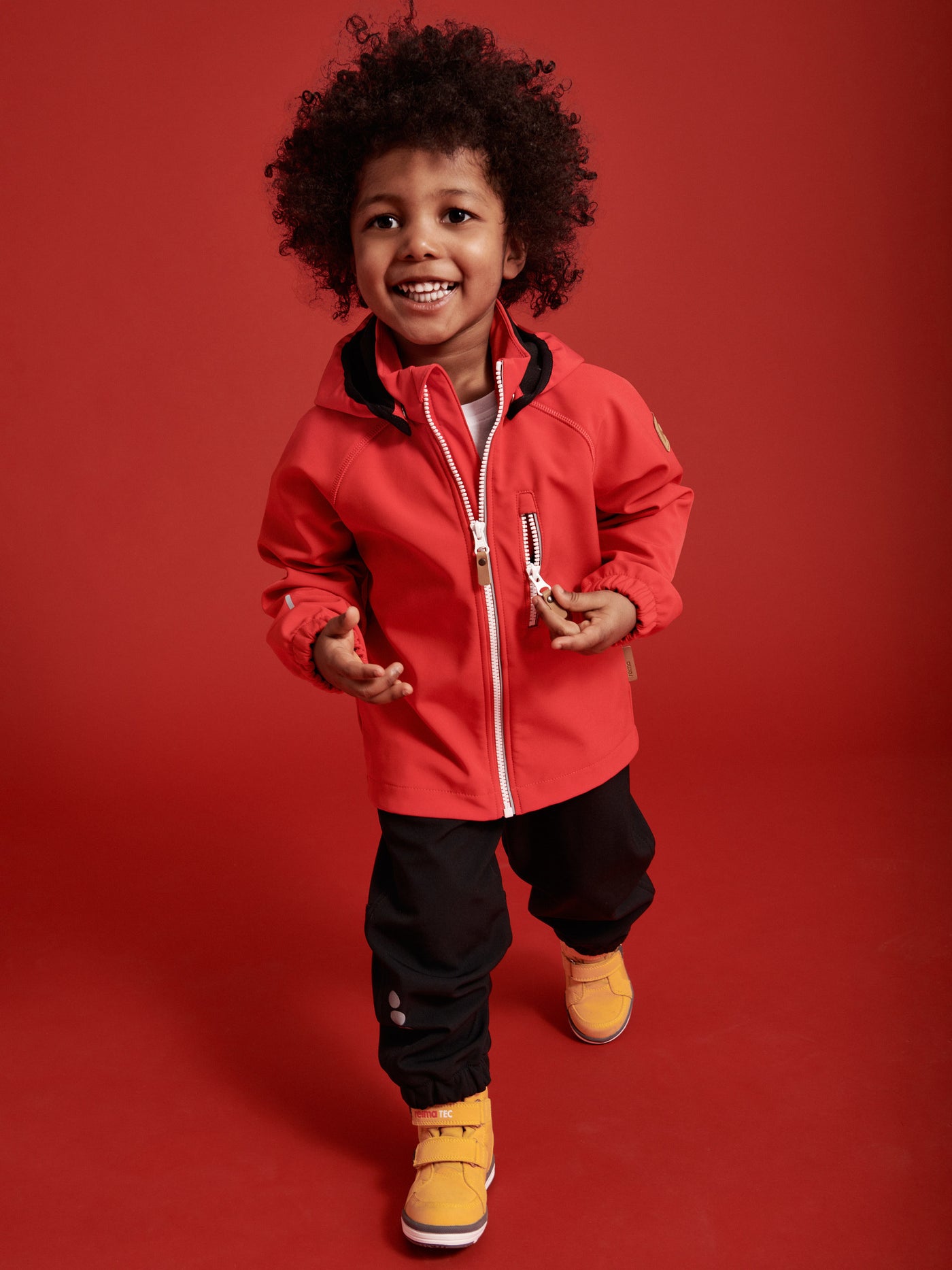 Reima Kuori lasten mustat softshell housut ja punainen Vantti takki pojan päällä
