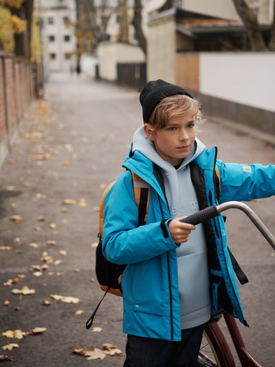 Sininen Reiman Reimatec Tieten -laskettelutakki pyöräilevän lapsen päällä kaupungissa 