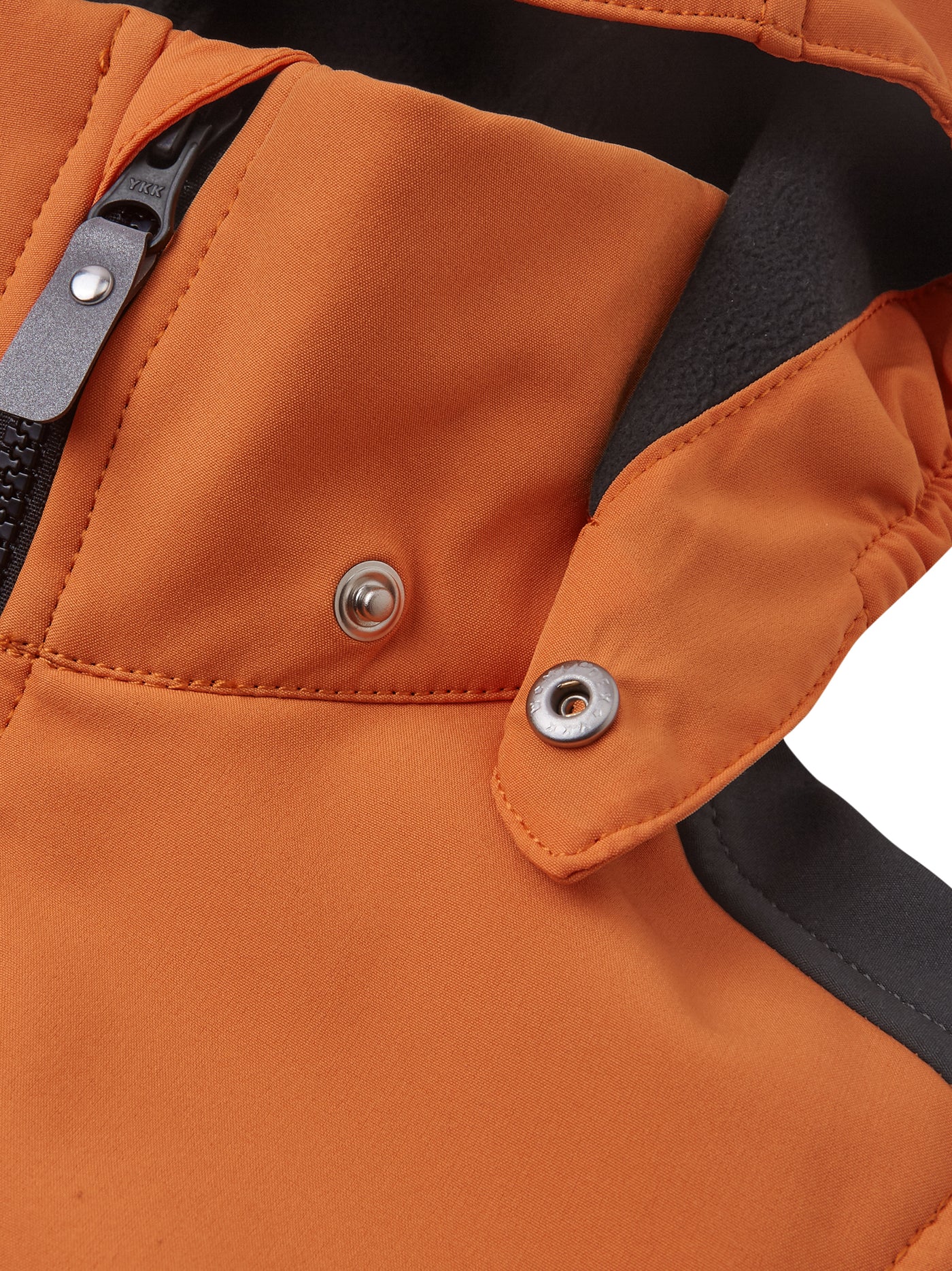 Reiman Sipoo Softshell-takki oranssin sävyssä lähikuvassa hupun nepparikiinnitys