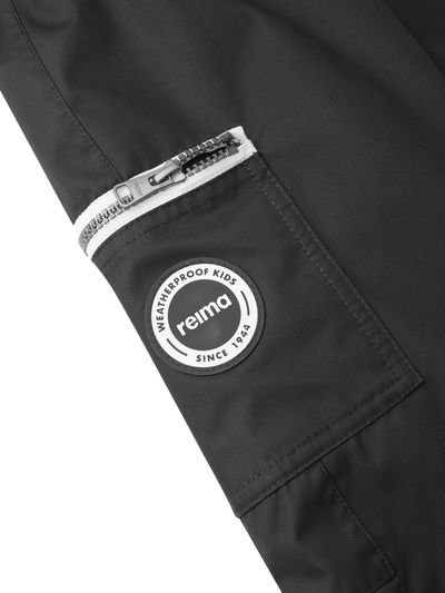 Reiman Reimatec Tiksi mustat kevyttoppahousut tasku ja Reima-merkki kuvattuna