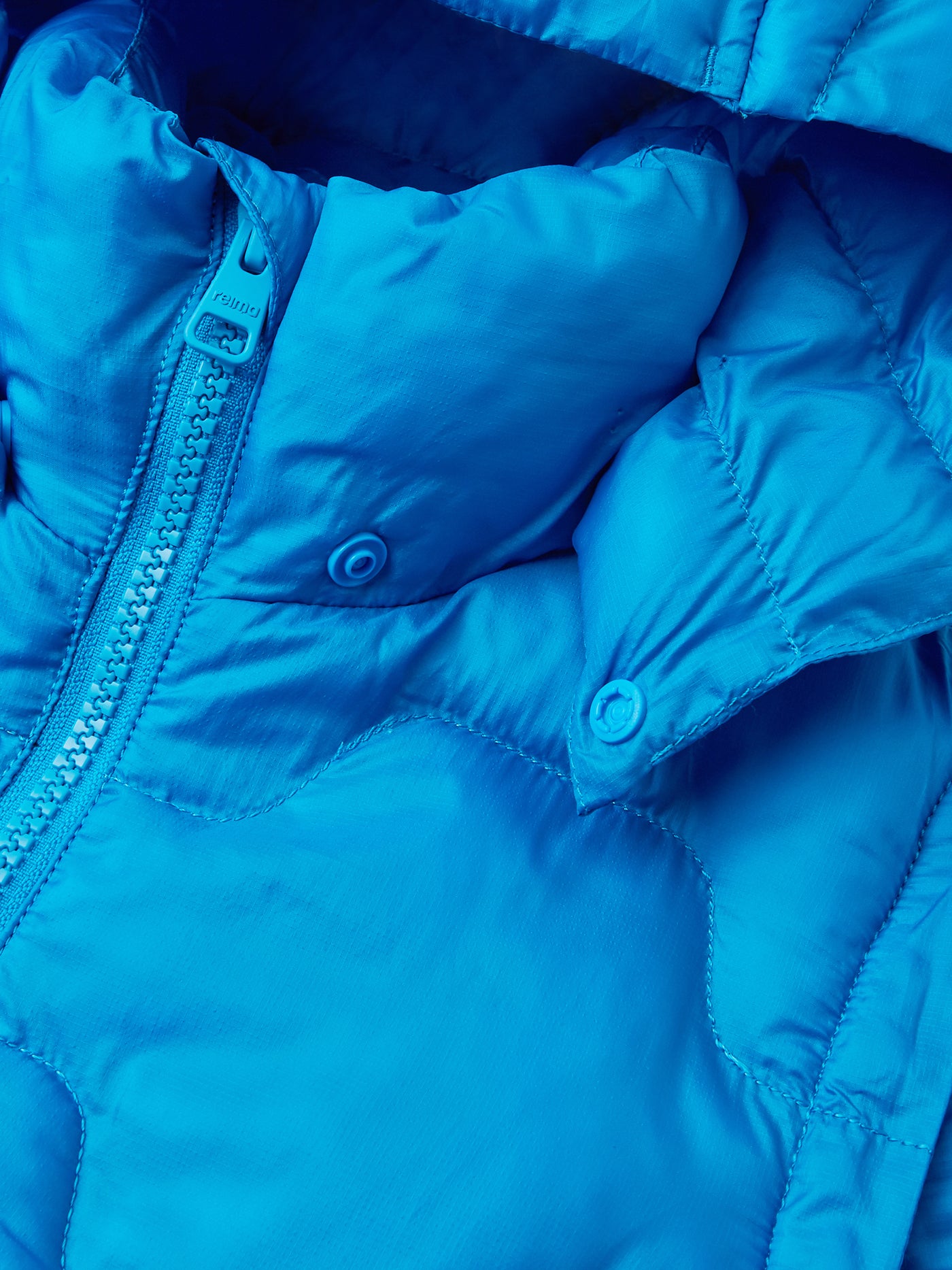 Reiman sinisestä Veke-kevyttoppatakista kuvattuna takin hupun neppari